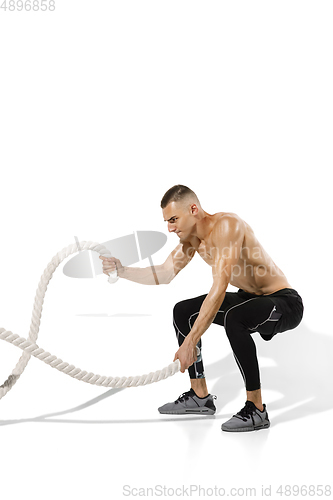 Image of Beautiful young male athlete practicing on white studio background with shadows