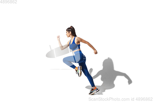 Image of Beautiful young female athlete practicing on white studio background with shadows