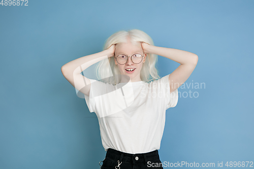 Image of Portrait of beautiful caucasian albino girl isolated on blue studio background