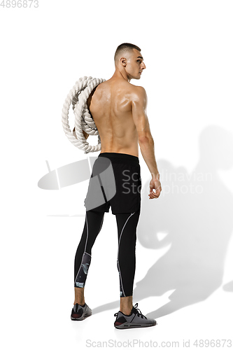 Image of Beautiful young male athlete practicing on white studio background with shadows