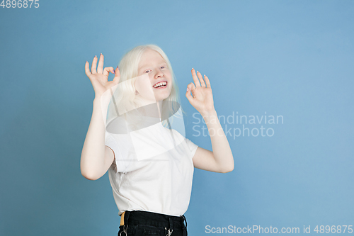 Image of Portrait of beautiful caucasian albino girl isolated on blue studio background