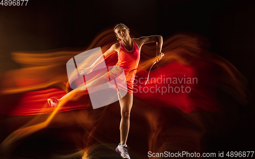 Image of Professional female tennis player isolated on black studio background in mixed light