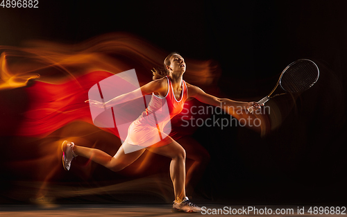 Image of Professional female tennis player isolated on black studio background in mixed light