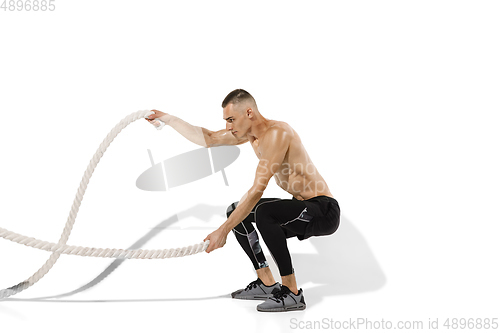 Image of Beautiful young male athlete practicing on white studio background with shadows