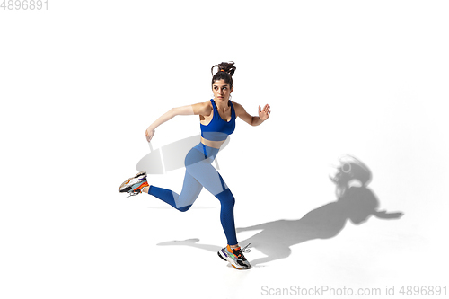 Image of Beautiful young female athlete practicing on white studio background with shadows