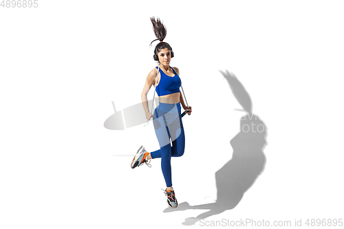 Image of Beautiful young female athlete practicing on white studio background with shadows