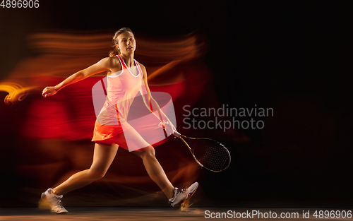 Image of Professional female tennis player isolated on black studio background in mixed light