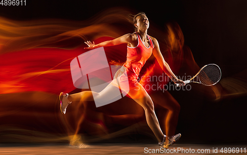 Image of Professional female tennis player isolated on black studio background in mixed light