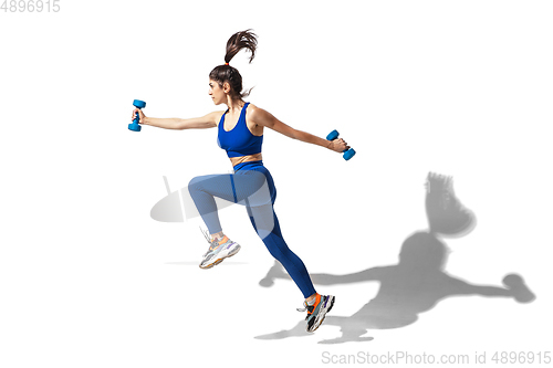 Image of Beautiful young female athlete practicing on white studio background with shadows