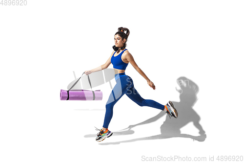 Image of Beautiful young female athlete practicing on white studio background with shadows