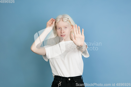 Image of Portrait of beautiful caucasian albino girl isolated on blue studio background