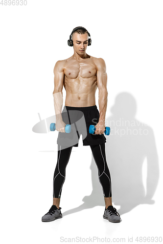 Image of Beautiful young male athlete practicing on white studio background with shadows