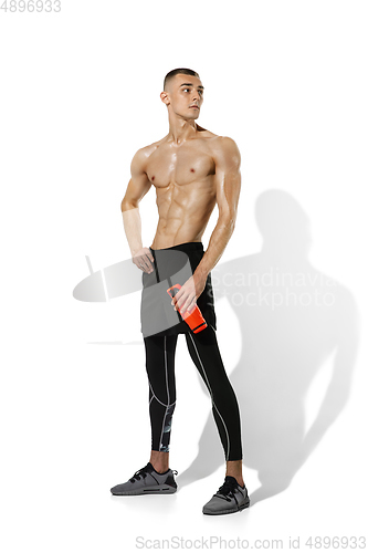 Image of Beautiful young male athlete practicing on white studio background with shadows