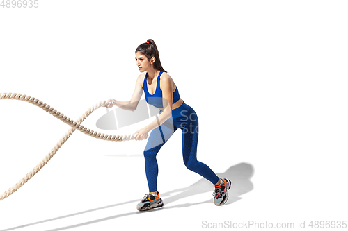 Image of Beautiful young female athlete practicing on white studio background with shadows