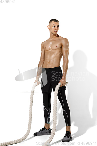 Image of Beautiful young male athlete practicing on white studio background with shadows