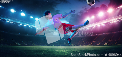 Image of Football or soccer player on full stadium and flashlights background