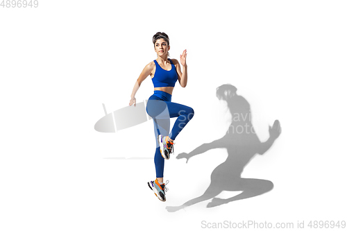 Image of Beautiful young female athlete practicing on white studio background with shadows