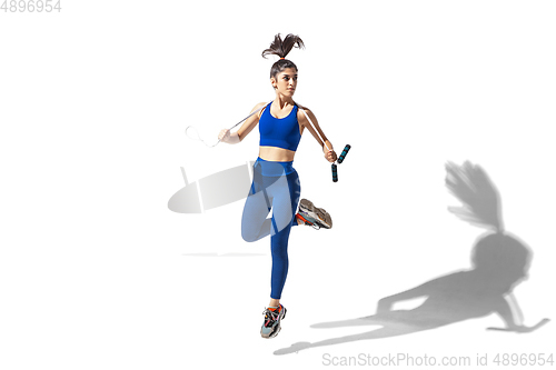 Image of Beautiful young female athlete practicing on white studio background with shadows