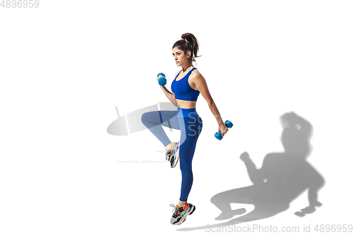 Image of Beautiful young female athlete practicing on white studio background with shadows