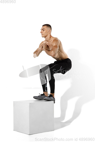 Image of Beautiful young male athlete practicing on white studio background with shadows