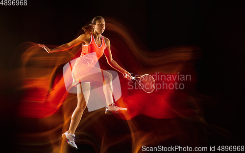 Image of Professional female tennis player isolated on black studio background in mixed light