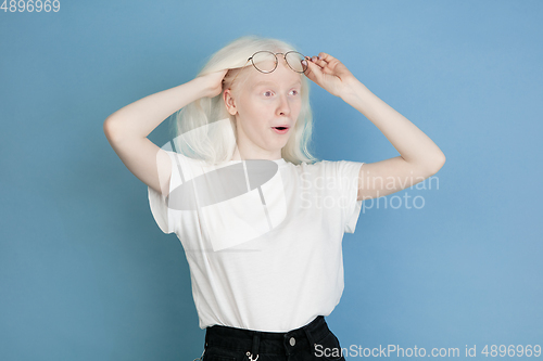 Image of Portrait of beautiful caucasian albino girl isolated on blue studio background