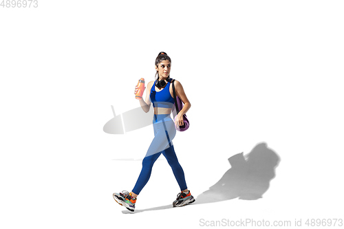 Image of Beautiful young female athlete practicing on white studio background with shadows