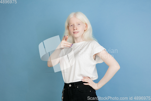 Image of Portrait of beautiful caucasian albino girl isolated on blue studio background