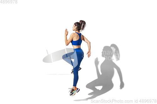 Image of Beautiful young female athlete practicing on white studio background with shadows