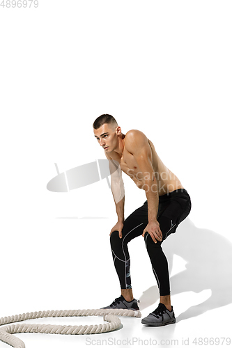 Image of Beautiful young male athlete practicing on white studio background with shadows