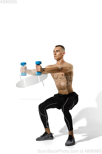 Image of Beautiful young male athlete practicing on white studio background with shadows