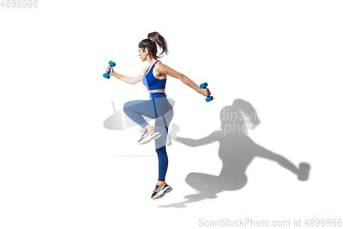 Image of Beautiful young female athlete practicing on white studio background with shadows