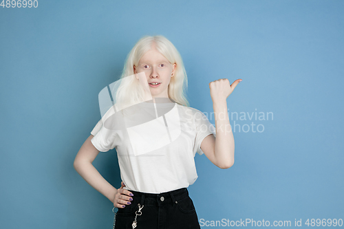 Image of Portrait of beautiful caucasian albino girl isolated on blue studio background