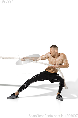 Image of Beautiful young male athlete practicing on white studio background with shadows