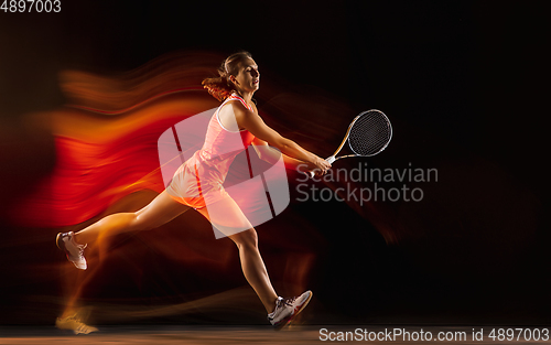 Image of Professional female tennis player isolated on black studio background in mixed light