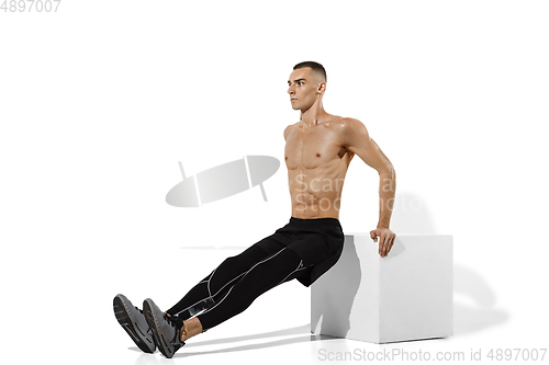 Image of Beautiful young male athlete practicing on white studio background with shadows