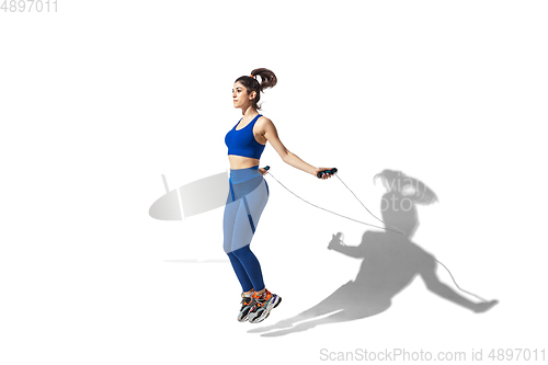 Image of Beautiful young female athlete practicing on white studio background with shadows