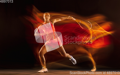 Image of Professional female tennis player isolated on black studio background in mixed light