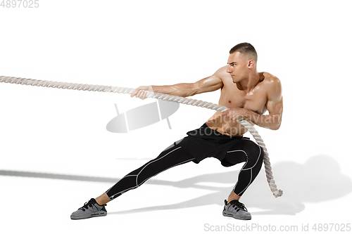 Image of Beautiful young male athlete practicing on white studio background with shadows