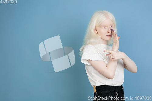 Image of Portrait of beautiful caucasian albino girl isolated on blue studio background