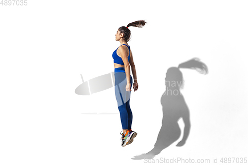 Image of Beautiful young female athlete practicing on white studio background with shadows