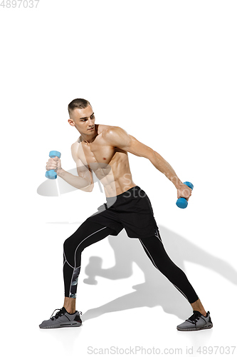 Image of Beautiful young male athlete practicing on white studio background with shadows