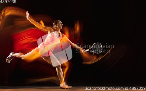 Image of Professional female tennis player isolated on black studio background in mixed light