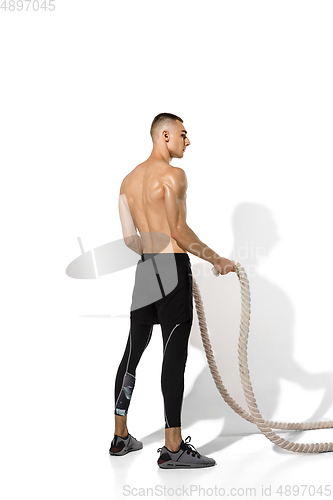 Image of Beautiful young male athlete practicing on white studio background with shadows