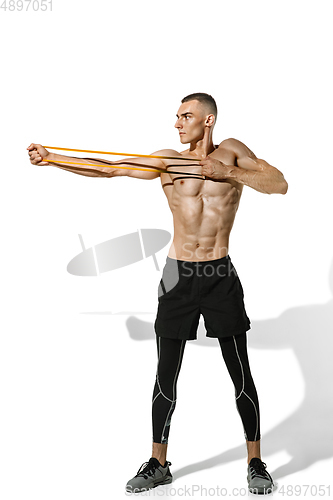 Image of Beautiful young male athlete practicing on white studio background with shadows