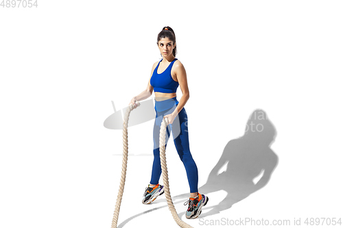 Image of Beautiful young female athlete practicing on white studio background with shadows