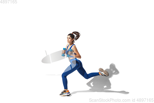 Image of Beautiful young female athlete practicing on white studio background with shadows