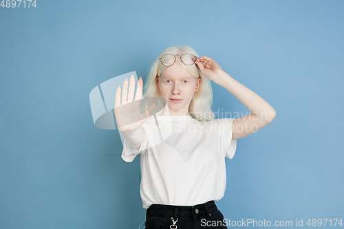 Image of Portrait of beautiful caucasian albino girl isolated on blue studio background