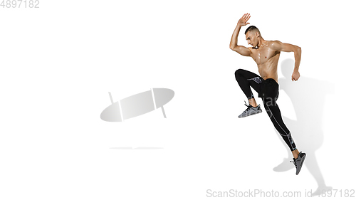 Image of Beautiful young male athlete practicing on white studio background with shadows