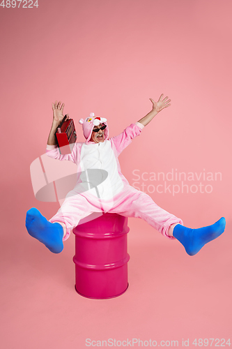 Image of Senior hipster man in stylish pink attire isolated on pink background. Tech and joyful elderly lifestyle concept